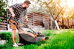 Gardening, industrial gardener starting the lawnmower and cutting grass in garden