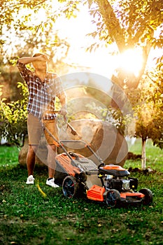 Gardening and landscaping details, worker, gardener using a with lawnmower and cutting grass in garden