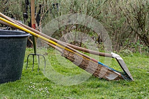 Gardening tools. Broom, shovel and rake on flowerpot in the garden