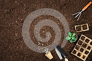 Gardening tools on fertile soil texture background top view.