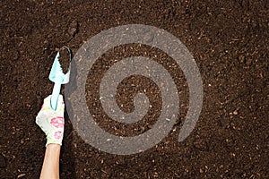 Gardening tools on fertile soil texture background top view.