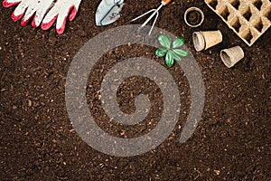 Gardening tools on fertile soil texture background top view.