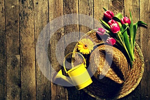 Gardening tools, flowers, watering can and straw hat on vintage