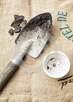 Gardening tools soil and pot plant on sack background