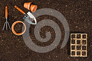 Gardening tools on soil texture background top view.