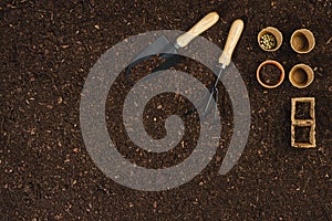 Gardening tools on soil texture background top view.