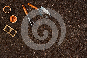 Gardening tools on soil texture background top view.