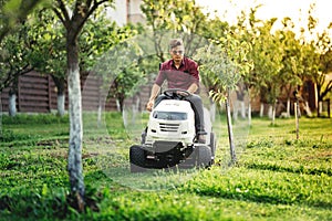 Gardner cutting grass, using professional rideon lawnmower and doing landscaping works