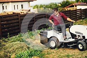 Gardner with lawn mower, professional worker cutting and unloading grass