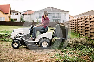 Gardner trimming and unloading cut grass from the garden using a ride on lawn mower