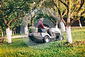 Gardner working and cutting grass in garden. Detail of landscaping works with lawnmower