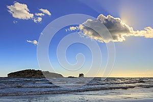 Gargano coast: Portonuovo beach,Vieste-Apulia ITALY-Islet between waves dominated by cloud crossed by sunbeams.