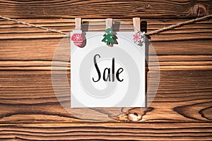 Garland with cute little kraft paper stickers hanging on a rope on wooden clothespins. Sale and promotion concept. Christmas