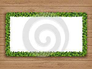 Garland frame made of green leaves on a wooden surface