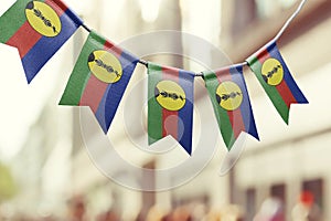 A garland of New Caledonia national flags on an abstract blurred background