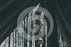 Garlands and kerosene lamp hanging on survival shelter in winter forest