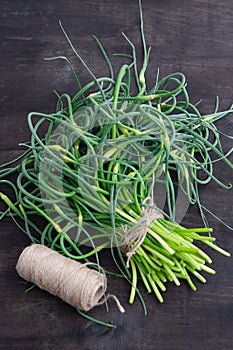 Garlic arrows. A bunch of greens on the table. Vegetable healthy vitamin food. Green stalks seedlings for salad and