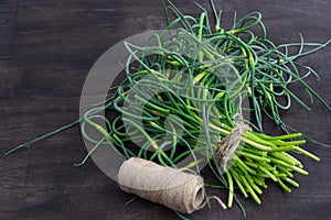 Garlic arrows. A bunch of greens on the table. Vegetable healthy vitamin food. Green stalks seedlings for salad and