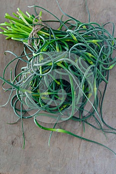 Garlic arrows. A bunch of greens on the table. Vegetable healthy vitamin food. Green stalks seedlings for salad and