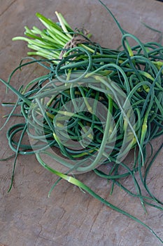 Garlic arrows. A bunch of greens on the table. Vegetable healthy vitamin food. Green stalks seedlings for salad and