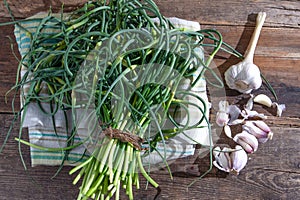 Garlic arrows. A bunch of greens on the table. Vegetable healthy vitamin food. Green stalks seedlings for salad and