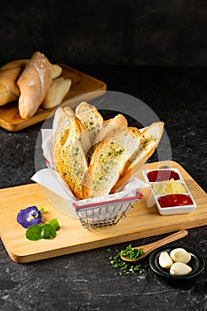 Garlic bread on basket with sauce and parsley condiment