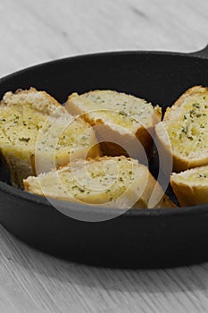 Garlic bread with herbs in a cast iron frying pan.