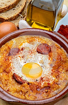 Garlic and bread soup Castilian, from Spain in clay pot and its main ingredients. View from above.