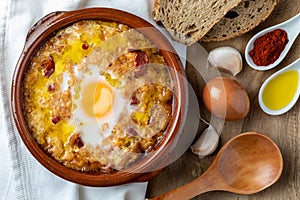 Garlic and bread soup Castilian, from Spain in clay pot and its main ingredients. View from above. Wood background