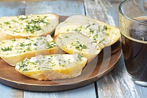 Garlic bread on the wooden plate with black coffee