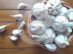 Garlic bulb on wicker basket on wooden background