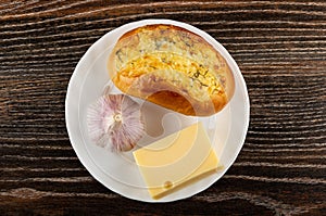 Garlic bun, piece of cheese and garlic head in  plate on wooden table. Top view