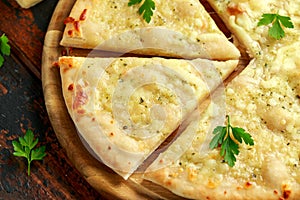 Garlic cheese pizza on wooden board with herbs.