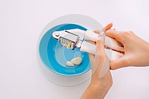 Garlic crushed using a garlic press. Female hands using a garlic press, crusher or mincer.