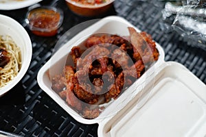 Garlic fried pork in a cardboard box on a black rattan table photo