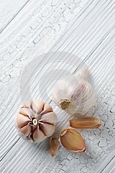 Garlic and garlic cloves on white wooden table