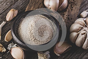 garlic and garlic powder on old wood, close up image