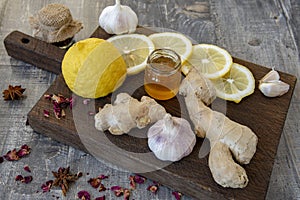 Garlic, lemon, honey, ginger and various spices on a rough wooden Board