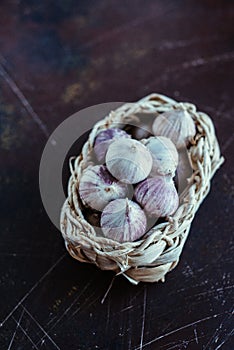 Garlic in a light wicker basket on a dark background