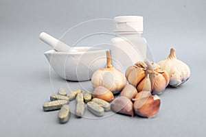 Garlic, Medicine grinding cup, Garlic tablet, White medicine bottle on gray background. Alternative medicine, herbal treatment