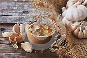 Garlic oil capsules in wooden bowl