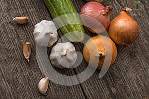 Garlic, onion, cucumber, potatoes and tomato on an old table