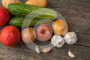 Garlic, onion, cucumber, potatoes and tomato on an old table