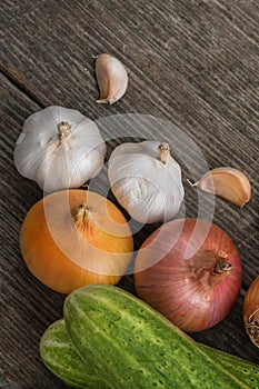 Garlic, onion, cucumber, potatoes and tomato on an old table