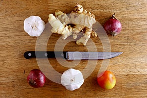 Garlic, onion, ginger, tomato and knife on a chopping board