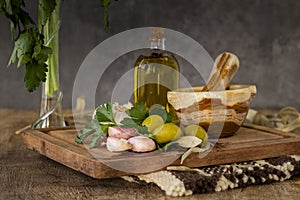Garlic, parsley and green olives on table with stone mortar.