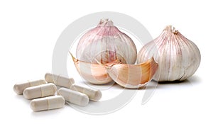 Garlic and pills capsule on white background