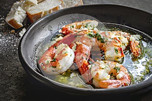 Garlic Prawns or Shrimp in black rustic bowl with crusty bread