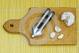 Garlic-press and bulb on wooden board