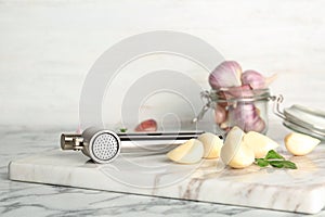 Garlic press and cloves on marble board